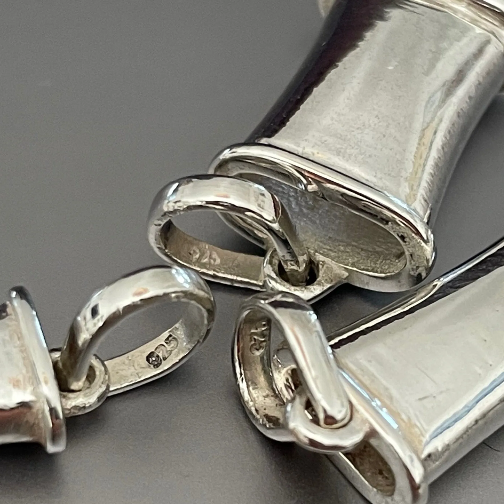 Macro detail of sterling silver Breathing Jewel pendants showing the open channel and 925 hallmark